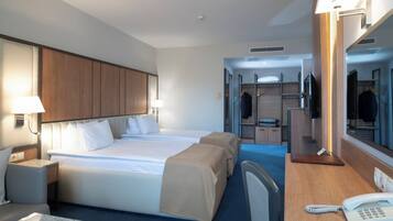 Une chambre d’hôtel avec un grand lit, des tables de chevet, un bureau avec un téléphone et un miroir.