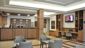 A hotel lobby with a reception desk, seating area, and a TV screen. - Legends Hotel Sofia (Sofia)