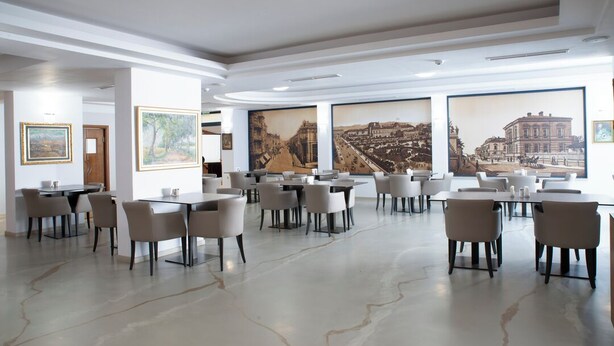 A spacious dining area with multiple tables and chairs, large framed artworks on the walls, and a modern ceiling design. - Legends Hotel Sofia (Sofia)