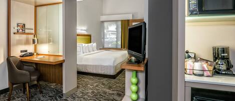A hotel room with a bed, a desk with a telephone, a television, and a coffee maker.