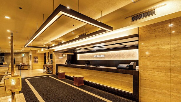 A hotel reception area with a modern design, featuring a reception desk, a digital check-in station, and a carpeted floor. - New Osaka Hotel (Osaka)