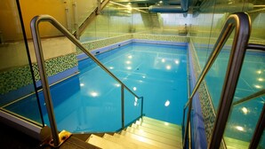 An indoor swimming pool with clear glass walls, metal railings, and tiled flooring. - Distinction Wellington Century City Hotel (Wellington)