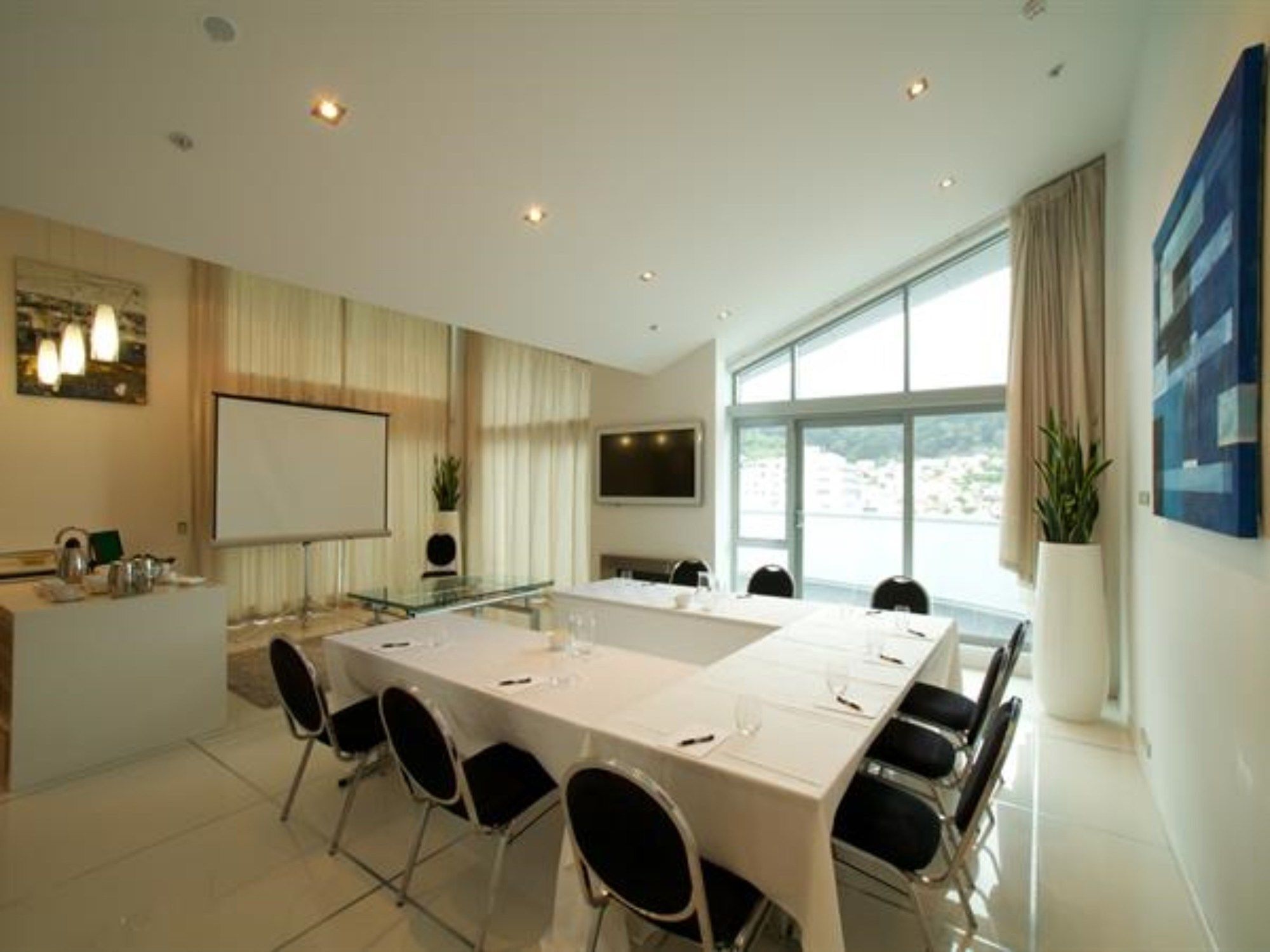 A conference room with a long table, chairs, a whiteboard, and a TV screen.