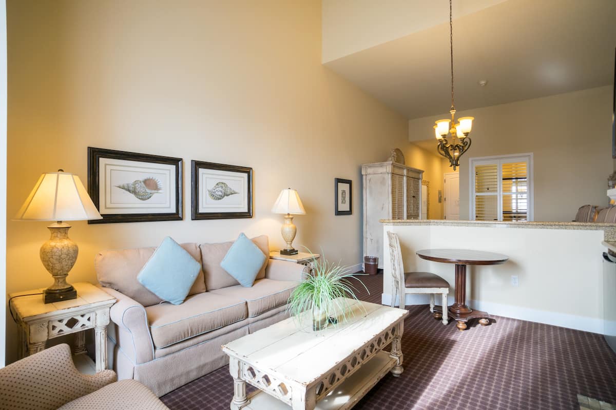 A living room with a sofa, two side tables with lamps, a coffee table, and framed artwork on the wall.