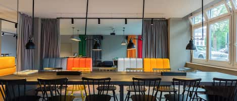 Un comedor moderno con una mesa larga y varias sillas, un sofá con cojines de colores e iluminación colgante.