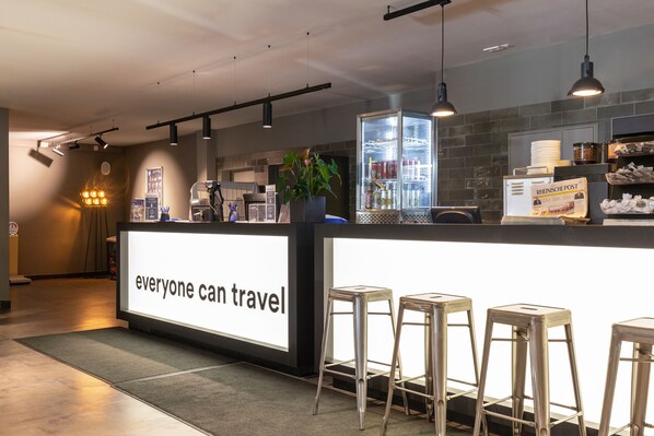 A modern bar area with a sign reading "everyone can travel" and a refrigerator stocked with beverages.
