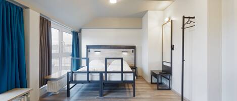 A modern bedroom with a bed, a radiator, a bench, and a mirror.