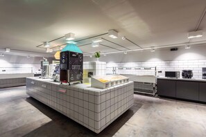 A modern coffee station with a coffee machine, a display case with coffee beans, and a small plant.