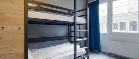 Habitación con literas, un armario de madera y una ventana con cortinas.