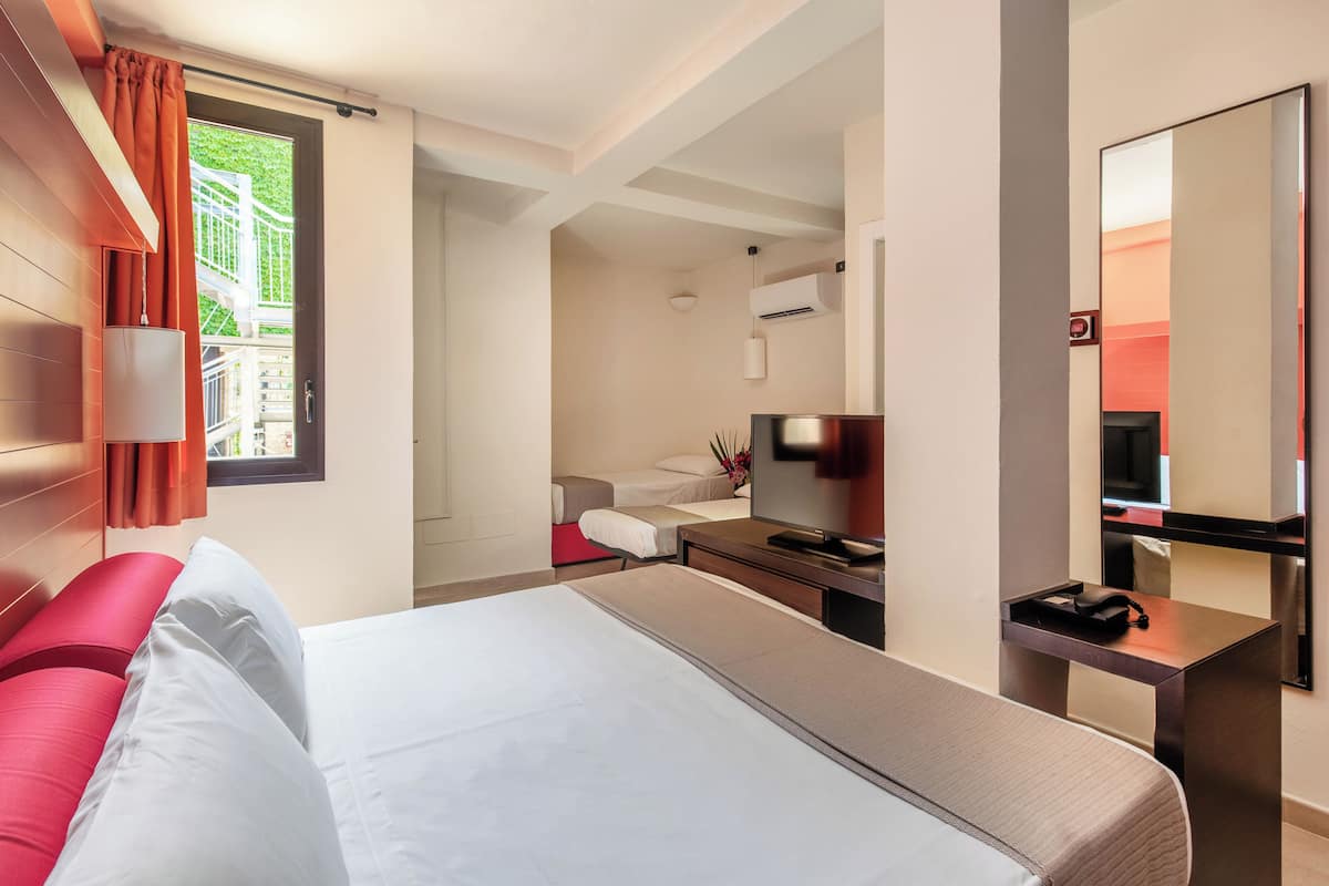 A hotel room with a bed, a desk, a TV, and a large mirror.