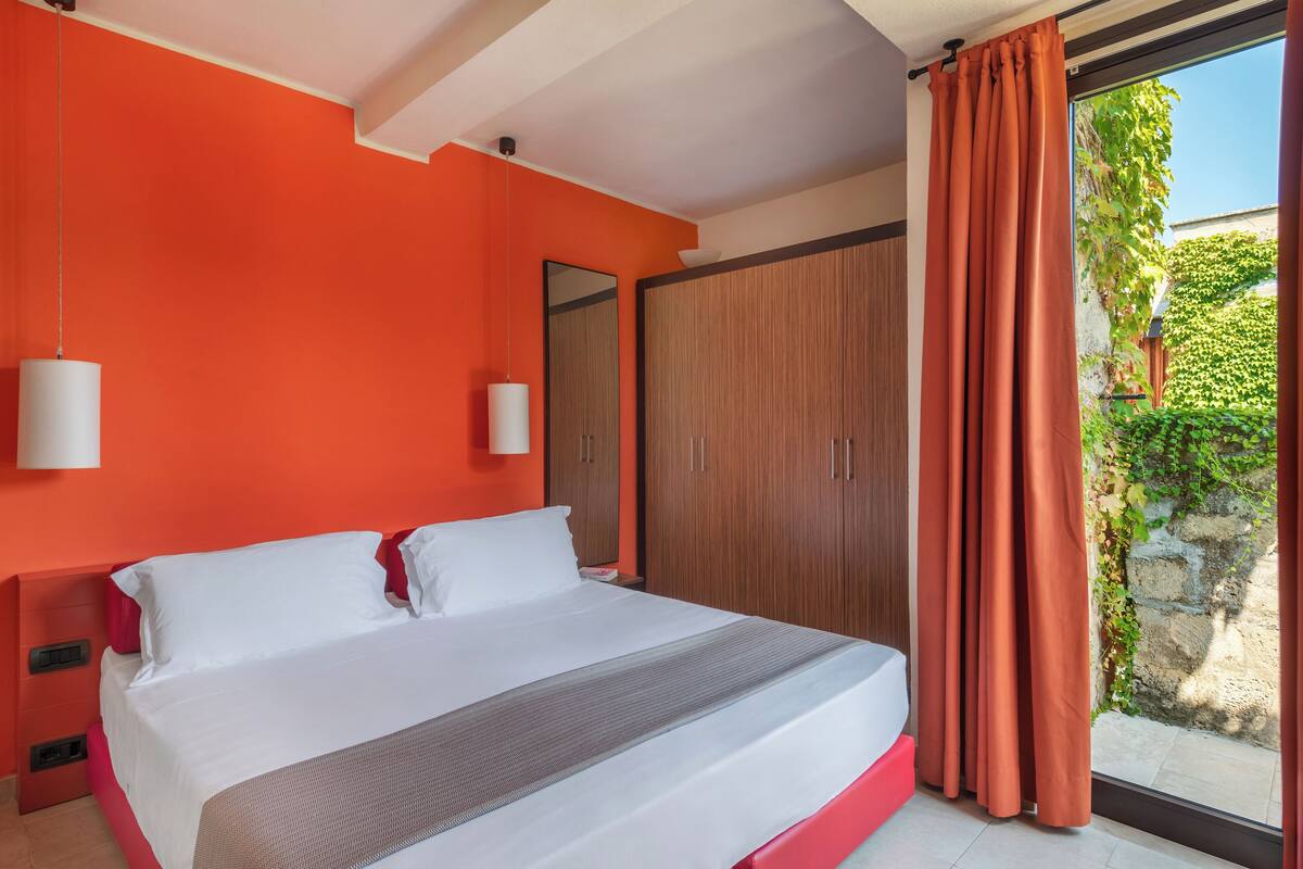 A bedroom with a large bed, a wardrobe, and a window with curtains.