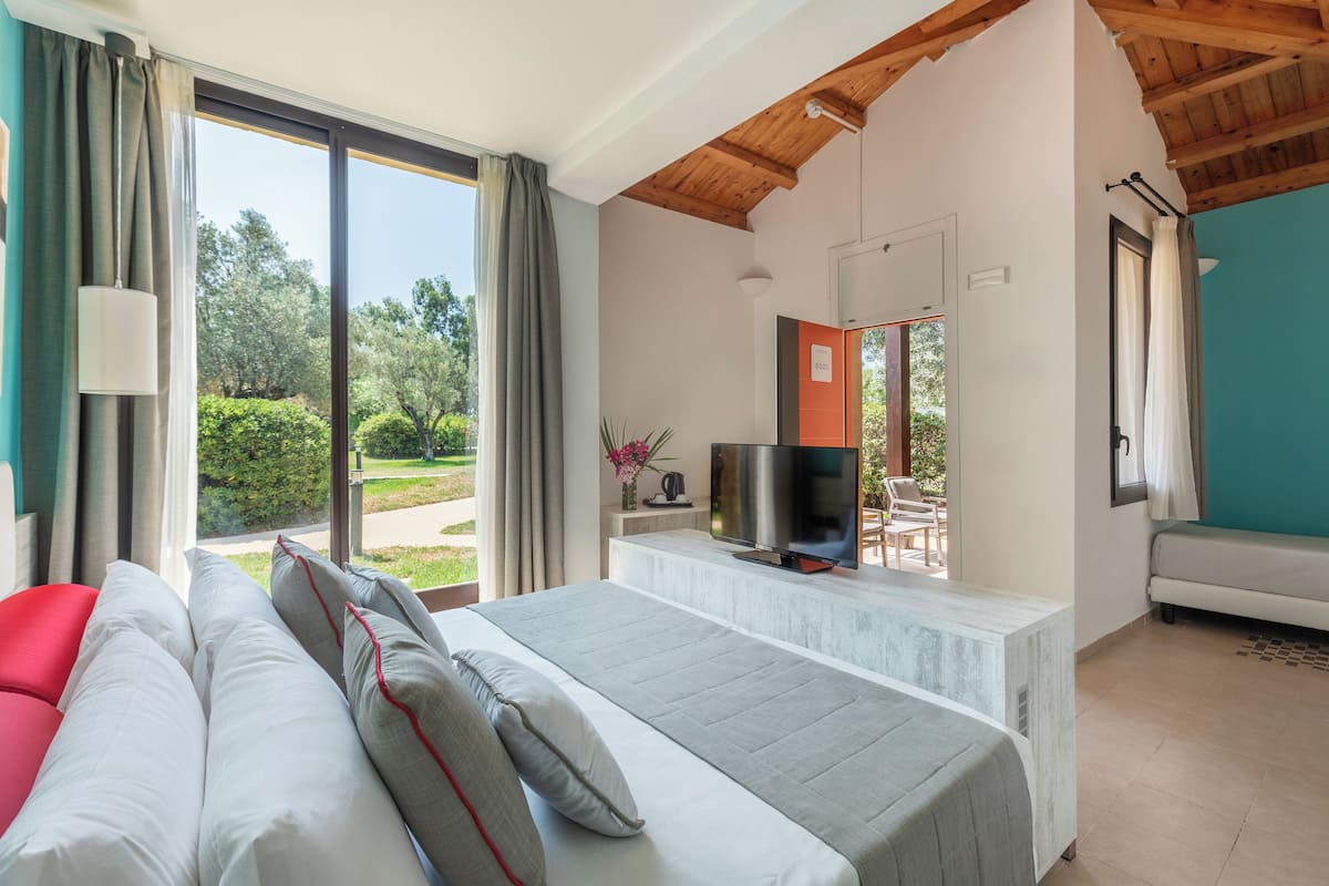 A bedroom with a bed, a TV, and a view of the outdoors.