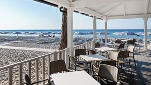 A beachside restaurant with outdoor seating and umbrellas, overlooking the beach and ocean. - VOI Floriana Resort (Simeri-Crichi)