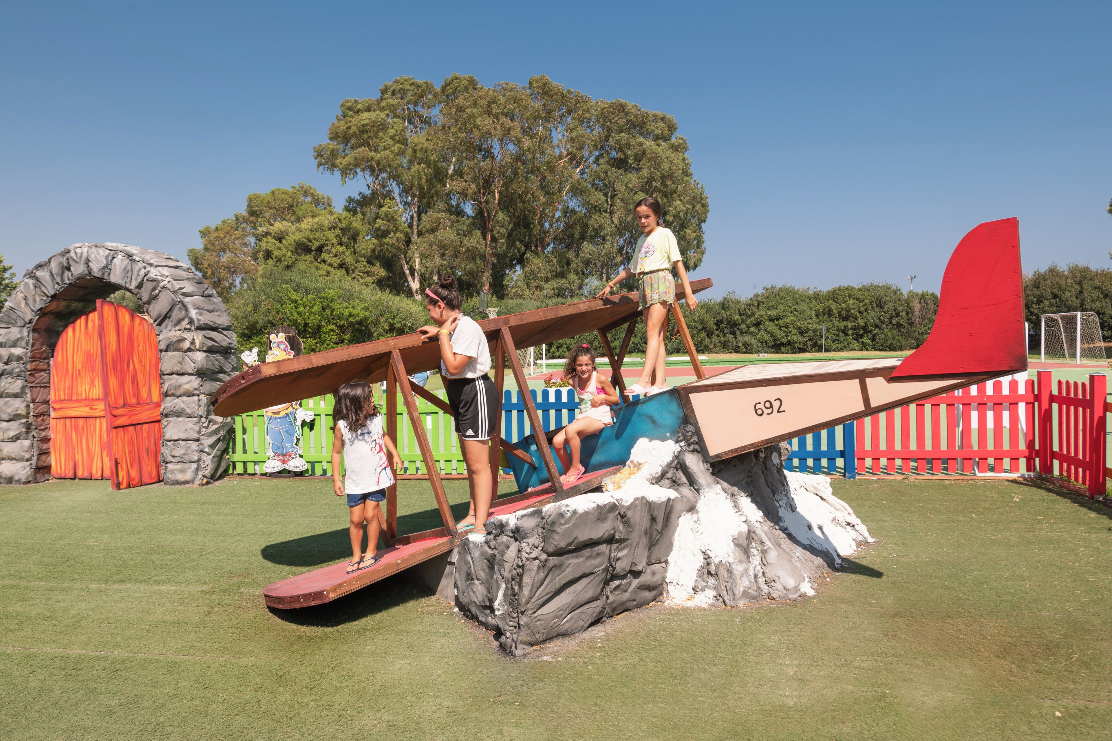Ein Spielplatz mit einer Wippe und einem roten Flugzeugmodell.