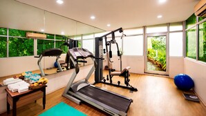 A gym with a treadmill, weight machines, and exercise balls. There are windows with a view of greenery. - Lords Inn Vadodara (Vadodara)