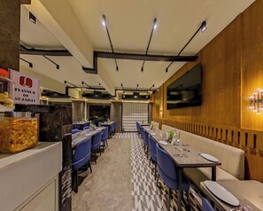 A restaurant with a checkered floor, blue chairs, and tables set for dining.