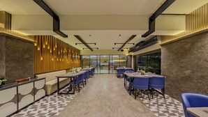 A modern hotel lobby with a checkered floor, a central seating area with tables and chairs, and a decorative wall with vertical lights. - Lords Inn Vadodara (Vadodara)