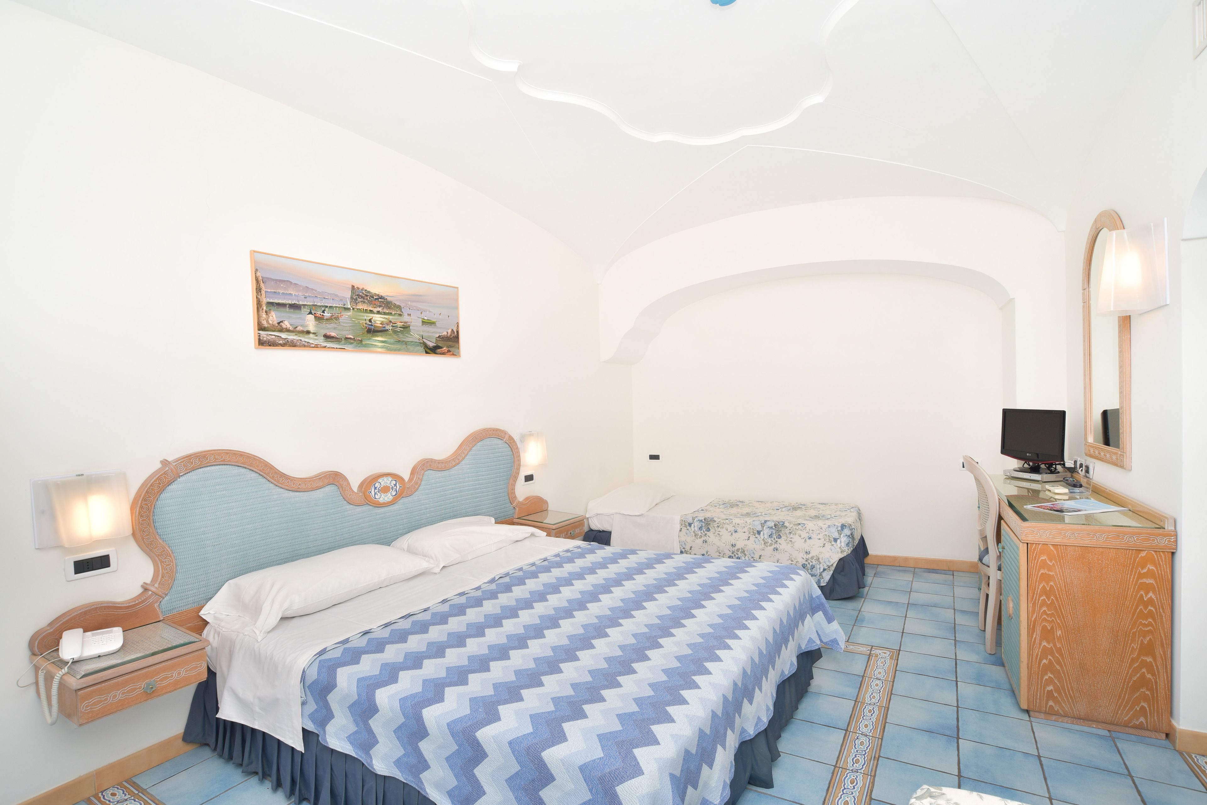 A bedroom with a bed, bedside tables, a desk, and a chair.