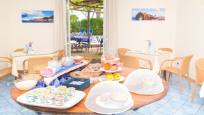 A breakfast buffet with various food items and a view of the outdoor seating area. - Albergo Terme Italia (Casamicciola Terme)