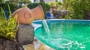 Ein Pool mit einer ungewöhnlichen Wasserattraktion, die an einen großen Tonkrug erinnert.