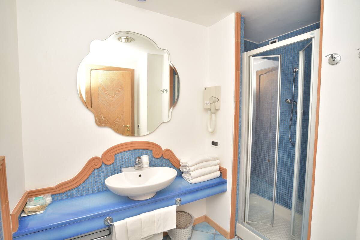 A bathroom with a sink, mirror, and shower.