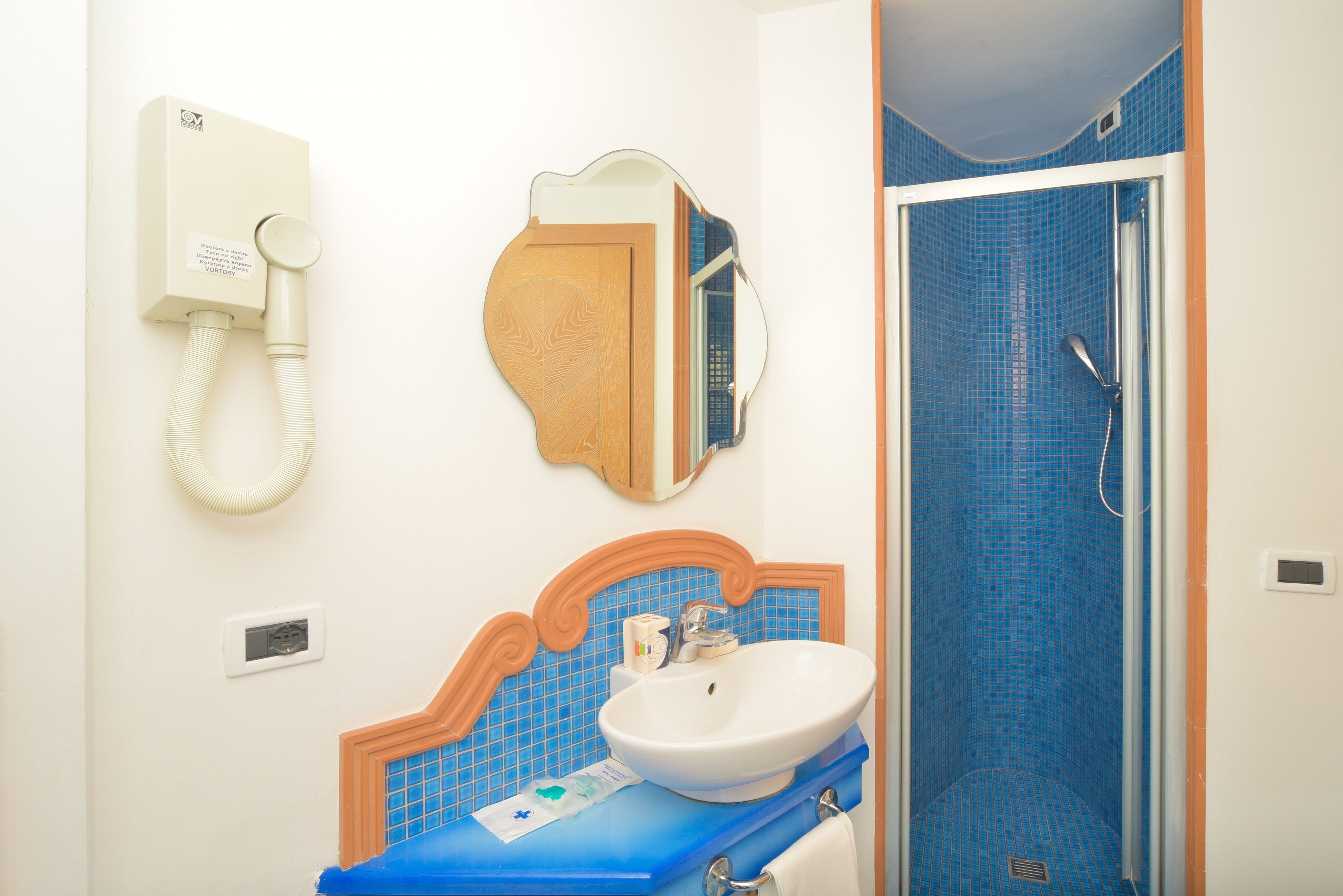 A bathroom with a sink, mirror, and shower.