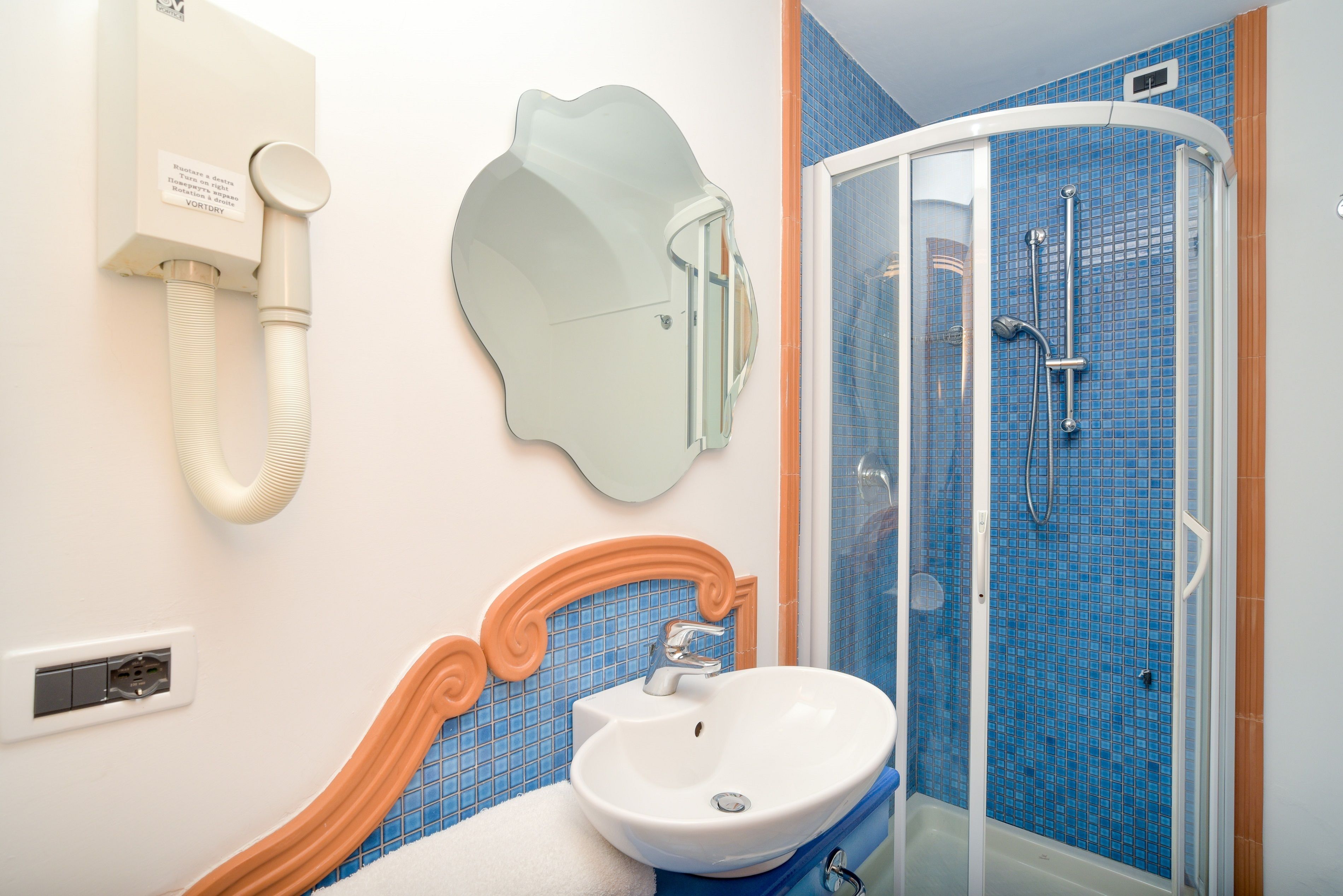 A bathroom with a sink, mirror, and shower.