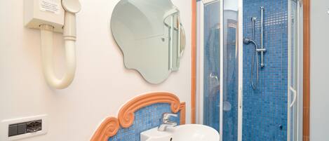 A bathroom with a sink, mirror, and shower.