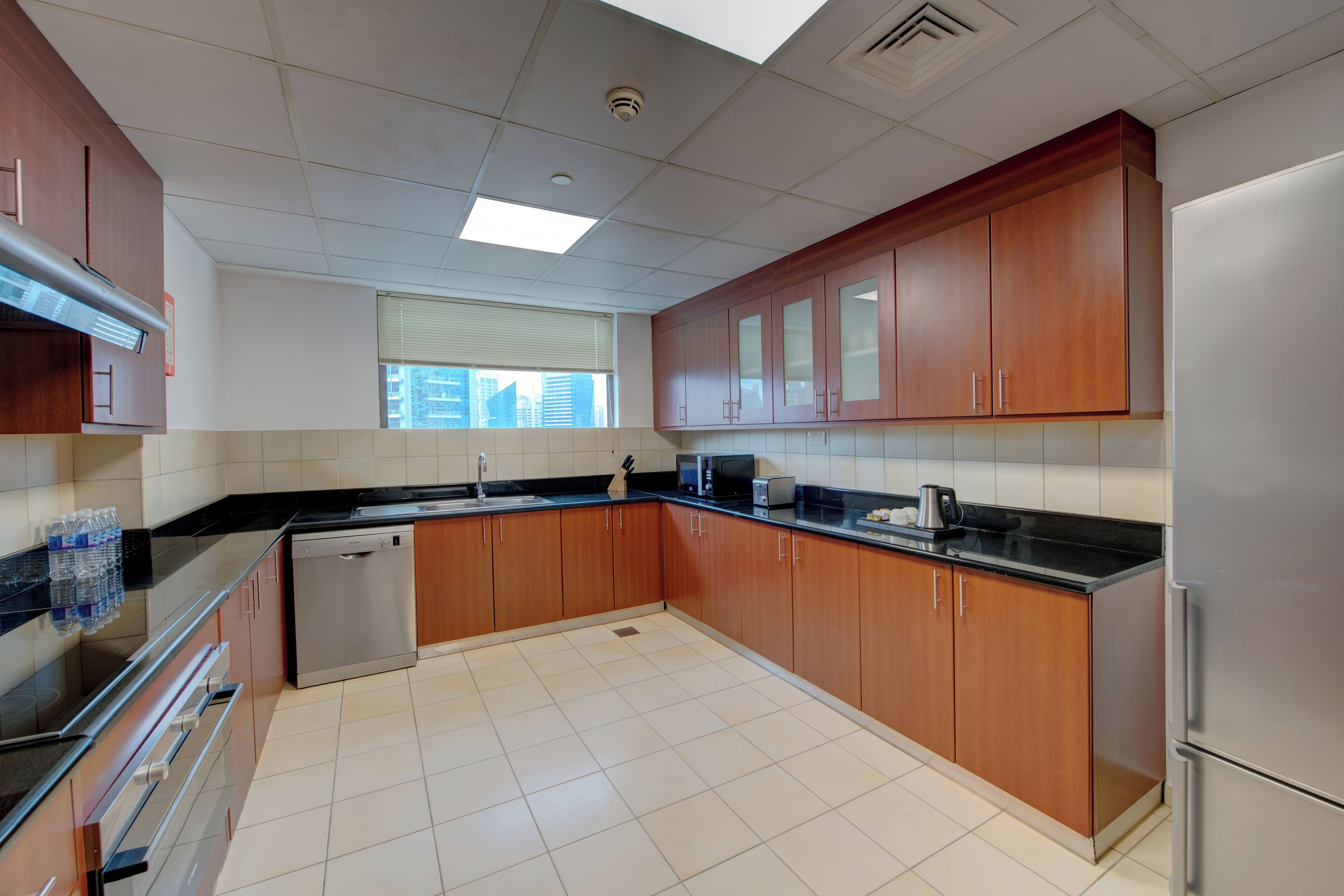 Una cocina moderna con armarios de madera, electrodomésticos de acero inoxidable y piso de baldosas.