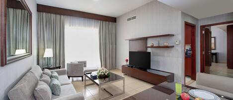 Una habitación de hotel moderna con sala de estar, comedor y televisor.