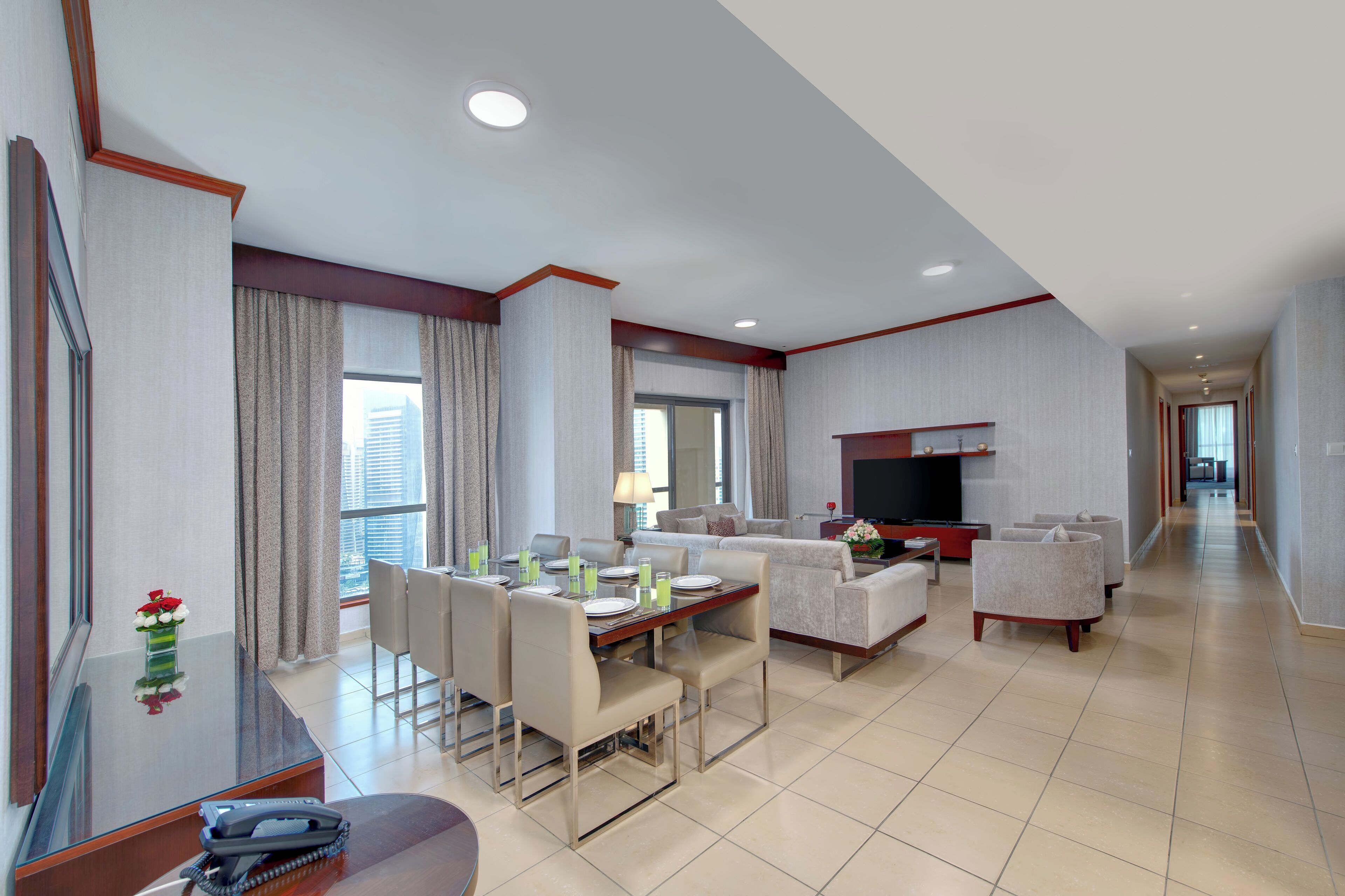 A modern hotel room with a dining area, a sofa, and a TV.