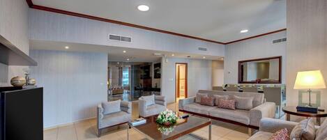 A spacious living area with a sofa set, a coffee table, and a television.