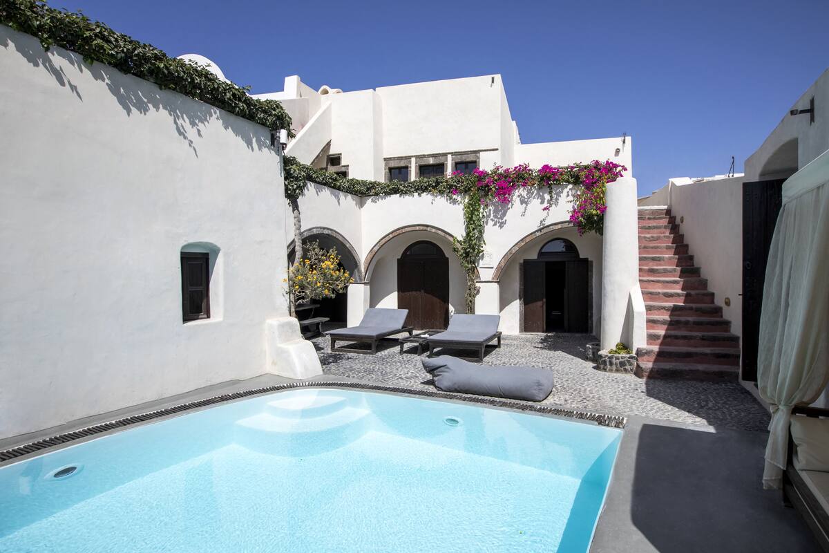 A pool area with lounge chairs and a staircase leading to an upper level.