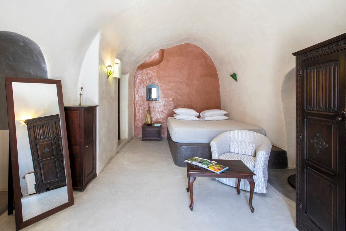 A bedroom with a bed, a nightstand, a mirror, and a wooden cabinet.