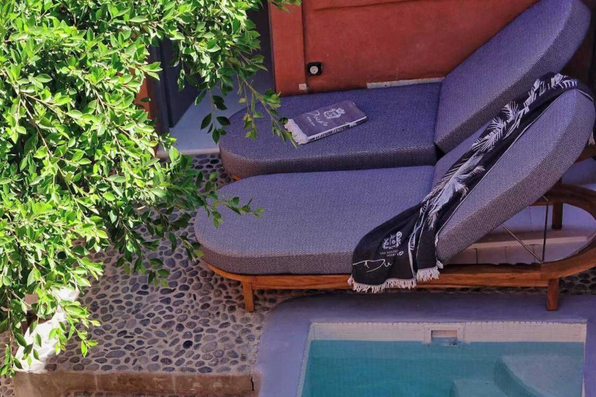 A poolside area with a stone-tiled deck, a small pool, lounge chairs, and towels.