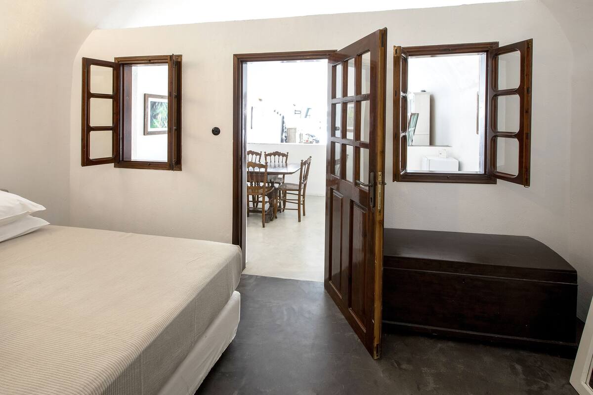 A bedroom with a bed, a bench, and two open windows.