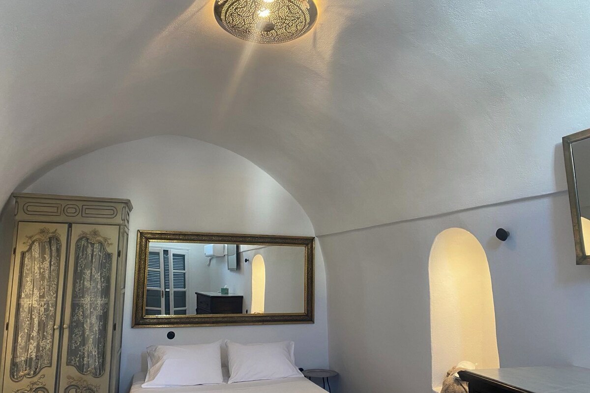 A bedroom with a bed, a wardrobe, a mirror, and a ceiling light fixture.