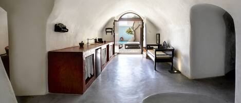 A narrow, arched hallway with a wooden counter and a bench.