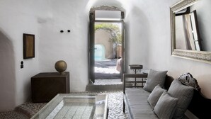 A modern interior with a sofa, a small table, and a decorative mirror. - Ducato Wine Village (Santorini)