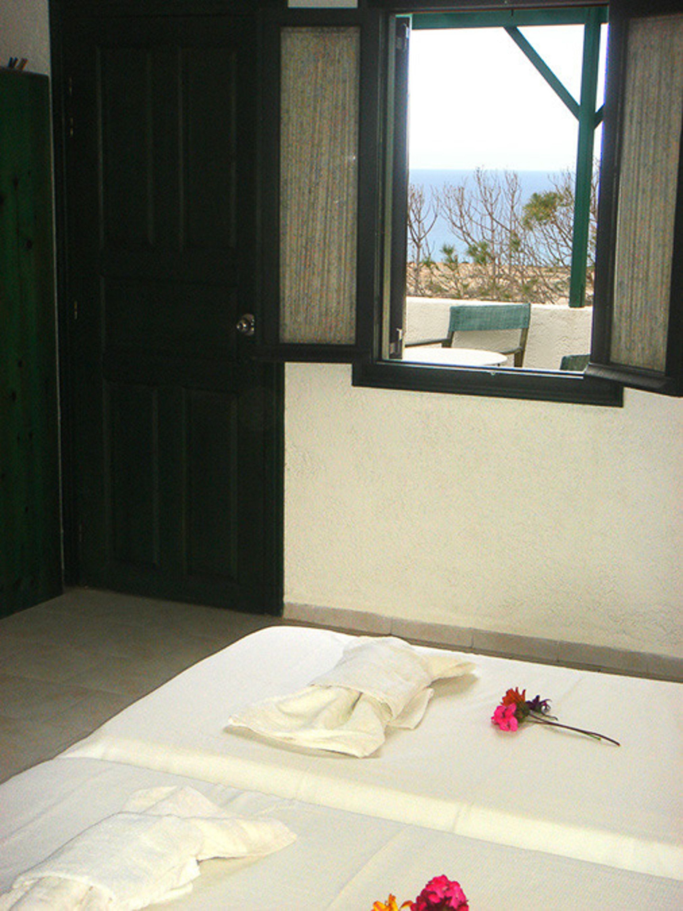 A room with a bed, a window with a view, and a green door.