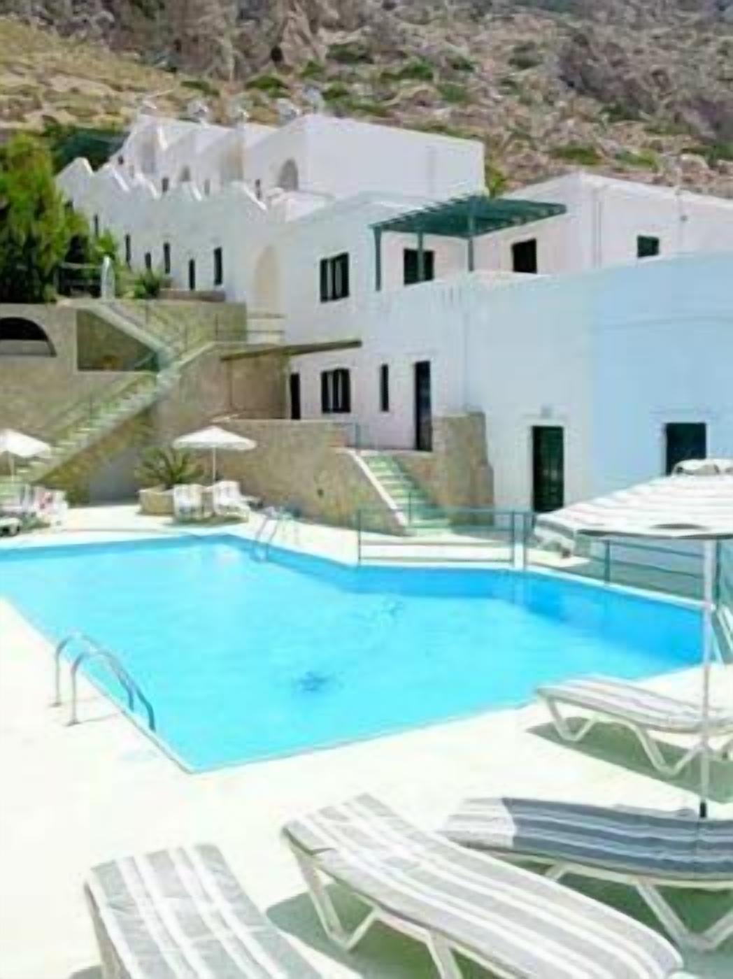 Área de piscina com espreguiçadeiras e um edifício branco com design arquitetônico singular.