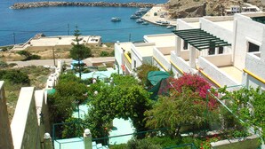 A coastal town with buildings overlooking the sea, a rocky outcrop, and a marina with boats. - Finiki View Hotel Apartments (Karpathos)