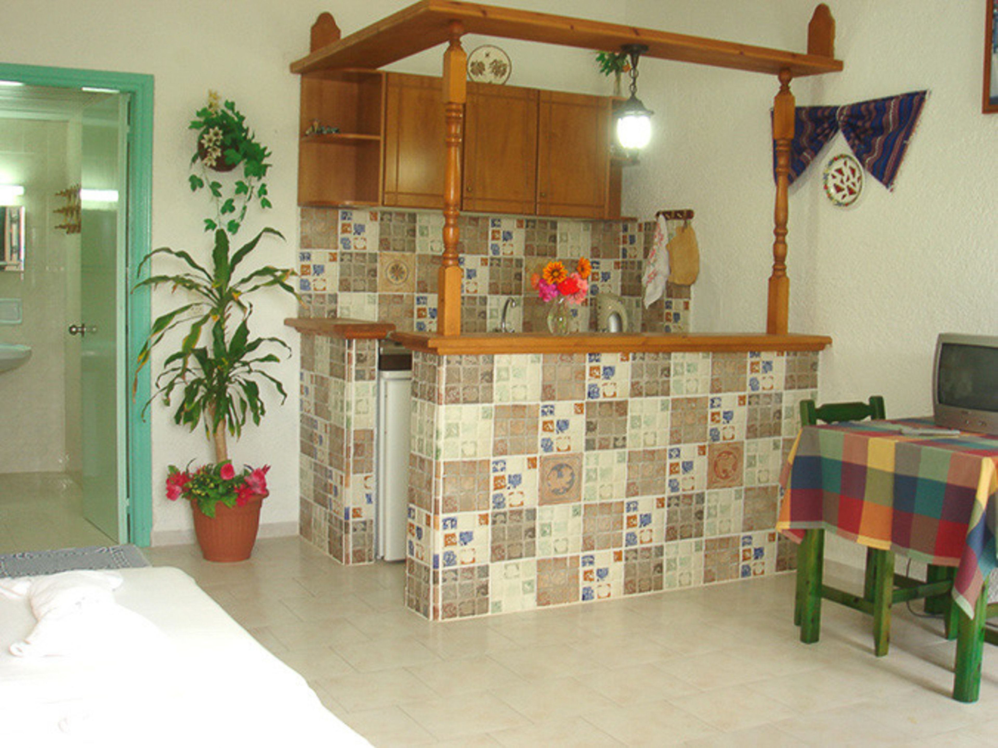 Una cocina con salpicadero de azulejos, armarios de madera, una isla de madera, un lavamanos y un comedor con mesa y sillas.