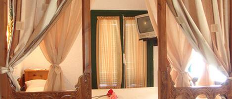 Un dormitorio con un espejo grande, muebles de madera, una cama, cortinas y un televisor.