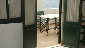 An open room with a bed, a table, and a view of the sea. - Finiki View Hotel Apartments (Karpathos)