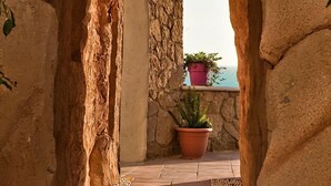 An arched stone doorway leading to a balcony with a potted plant. - Finiki View Hotel Apartments (Karpathos)
