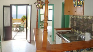 A kitchen with a wooden bar, a sink, and a view of the patio. - Finiki View Hotel Apartments (Karpathos)
