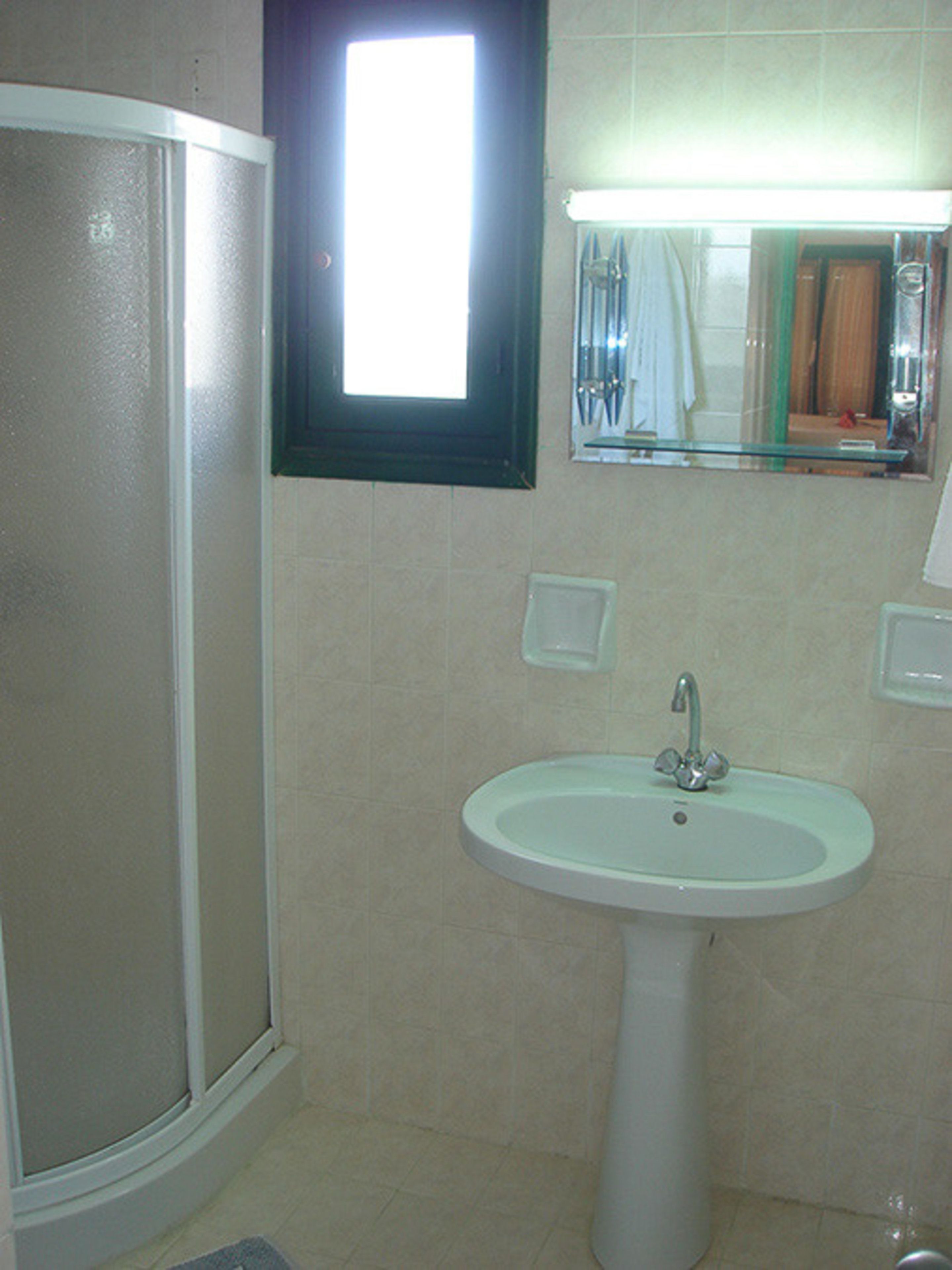 Ein Badezimmer mit Dusche, Waschbecken und Spiegel.