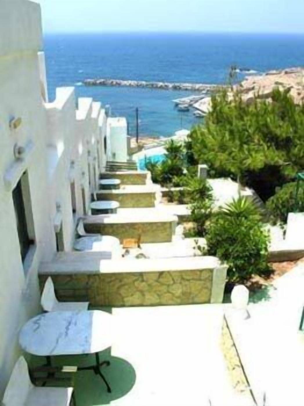 A coastal hotel with a pool, outdoor seating, and a view of the sea.