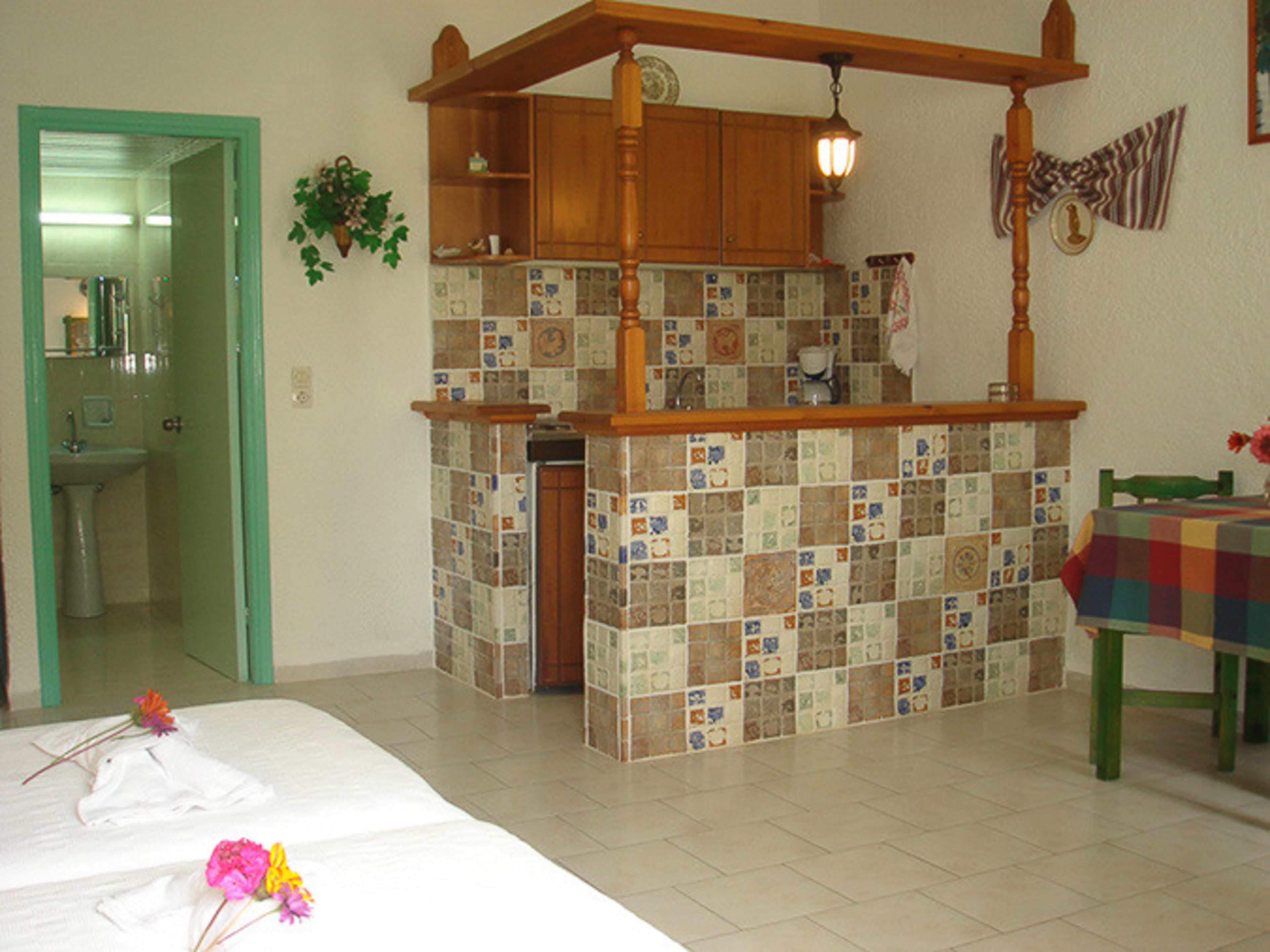 Una cocina con salpicadero de azulejos, armarios de madera y una lámpara colgante.